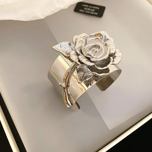 Macro shot of a silver metal cuff bracelet featuring a 3D sculpted rose flower detail