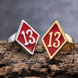 Macro view of punk style stainless steel rings with red enamel number 13 on bark base