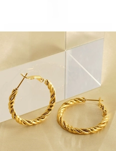 Macro detail of 18K gold plated spiral hoop earrings on gold silk background