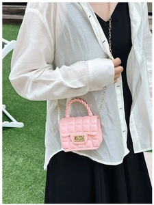 Close-up of pink quilted jelly handbag with gold chain strap on a natural background
