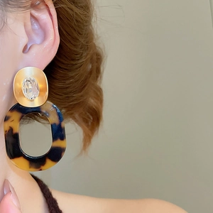 Close-up of vintage large resin leopard print earrings worn by model for retro style