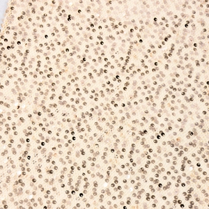 Gros plan de paillettes dorées champagne cousues sur du tissu en maille pour les robes