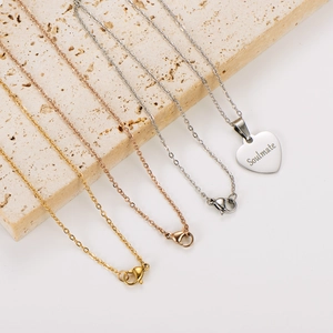 Detailed shot of three stainless steel necklaces with a soulmate heart pendant on stone