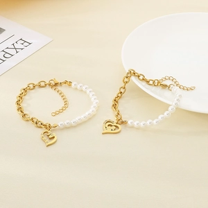 Detail of heart pendant bracelet with gold chain, white pearls and zircon inlay