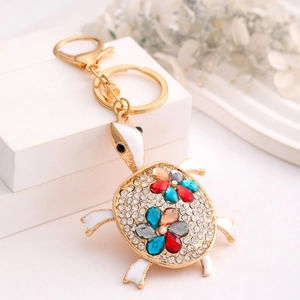 Macro view of gold turtle keychain featuring sparkling rhinestones and floral pattern stones