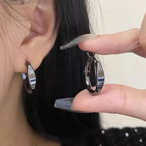 Close-up of gunmetal grey minimalist twisted metal hoop earring on model's ear