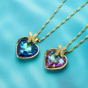 18K gold plated heart crystal necklace with dragonfly and bow accents on silk background