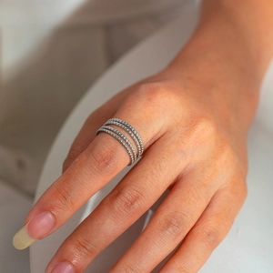 Close-up of a silver multi-layered beaded ring on finger with polished finish