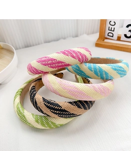 Detail of four colorful striped woven headbands stacked on a white minimalist table