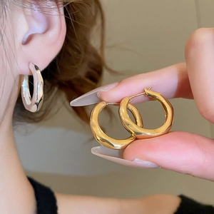 Detail of 18K gold and silver plated chunky hoop earrings with textured ripple design