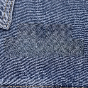 Macro shot of five black and yellow sarcasm themed enamel pins on blue denim fabric