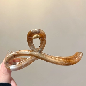 Detailed close-up of amber marble acrylic hair claw clip with golden spring component