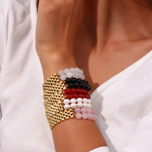 Close-up of gold mesh bracelet styled with colorful bead layers on a female model wrist