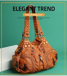 Detail view of vintage brown leather handbag with multiple zipper pockets and rivets