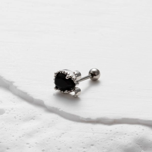 Dettaglio macro dell'orecchino in acciaio inossidabile con zircone nero e chiusura a vite