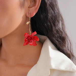 Macro detail of elegant red floral drop earring on model featuring gold branch design
