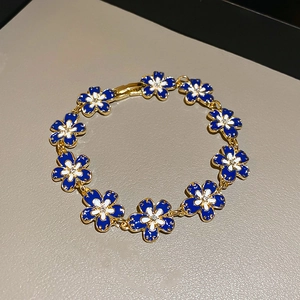 Detail of blue enamel flower bracelet with gold plating and white zircon centers