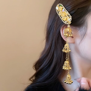 Detail of ethnic golden hair clip with hollow floral pattern and tassel bell charms