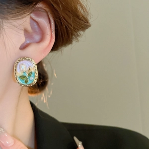 Detail of vintage enamel flower earring with pearl on ear for elegant styling