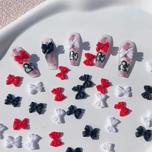 Detailed macro view of 3D resin bow nail charms in red, black and white on nail tips