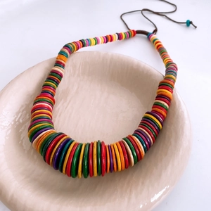 Detail of bohemian wooden disc beads and braided cord on a colorful ethnic necklace
