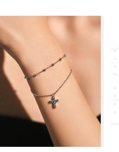 Close-up of double-layered S925 silver beaded bracelet with a sparkling cross pendant