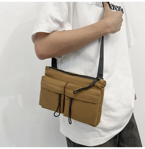 Brown nylon messenger bag shown on model with dual front pockets and adjustable strap