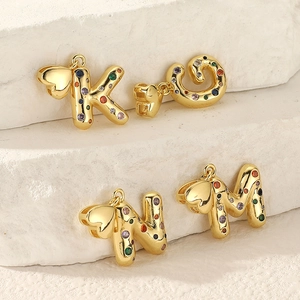 Close-up of gold plated letter pendants K O N M with colorful cubic zirconia stones