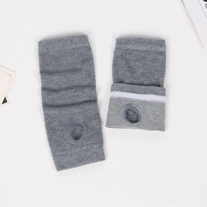 Detail view of grey knit fingerless gloves showing ribbed texture and thumb hole design