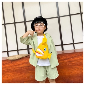 Close-up of yellow shark-shaped crossbody bag paired with a green linen kids outfit