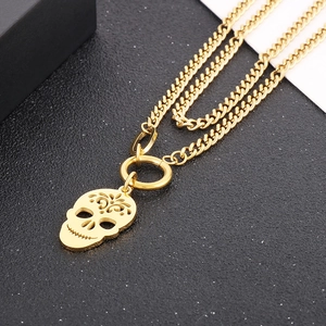 Detailed macro view of a gold skull pendant with intricate engravings on a Cuban chain