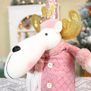 Close-up of pink Christmas reindeer doll with sequins and gold antlers in festive setting