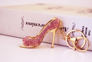 Detailed view of pink rhinestone high heel keychain with gold plating on an open book