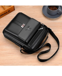 Close-up of black leather messenger bag with embossed logo and metal zipper detailing