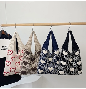 Détail montrant quatre grands sacs cabas tricotés avec motifs de fleurs et de cœurs variés