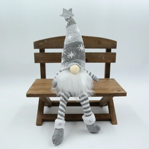 Détail d'un gnome de Noël gris avec motif flocon et étoile assis sur un banc en bois