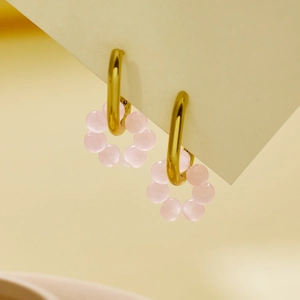 Detail der goldenen Creolen mit rosa Perlen und Emaille-Blumenanhängern für Damen