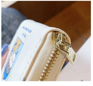 Close-up of cream PU leather card wallet with gold zipper and cute cat illustration