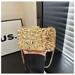 Close-up of golden clutch bag with pleated texture and thin metal chain strap