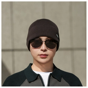Détail d'un bonnet en maille côtelée pour homme avec logo métallique et texture chaude