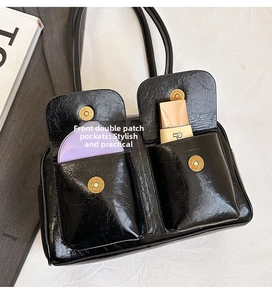 Detail of black crossbody bag with double front pockets and magnetic closures for storage