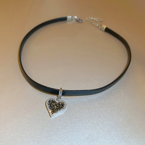 Detail of heart choker with black leather strap and sparkling crystal heart pendant