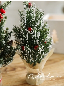 Close-up of mini snowy Christmas tree with red berries and burlap base for desk decor