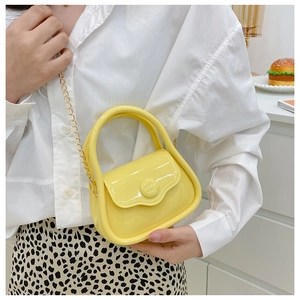 Macro view of bright yellow glossy mini bag with gold chain strap shown on a shoulder