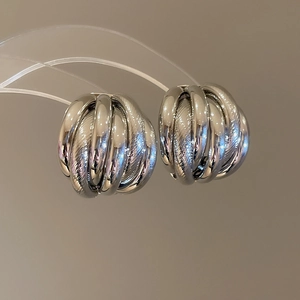 Detail view of silver layered spherical stud earrings with textured multi-ring design