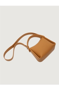Detail shot of a brown leather pillow bag with structured handle and detachable shoulder strap