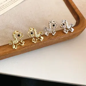 Hollow horse stud earrings in gold and silver finish on a wooden display tray