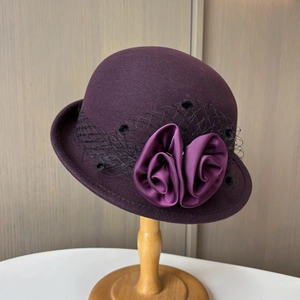 Detail of dark purple wool felt cloche hat with black mesh veil and satin flowers