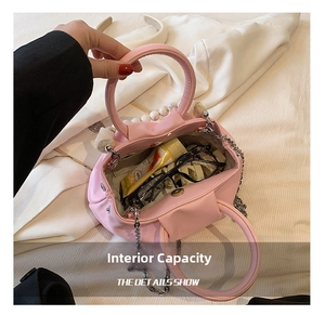 Detail of pink pleated cloud bag interior with pearl handle, chain, and inner capacity