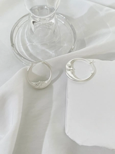Close-up of matte silver crescent moon earrings with rhinestone eyes on stone base